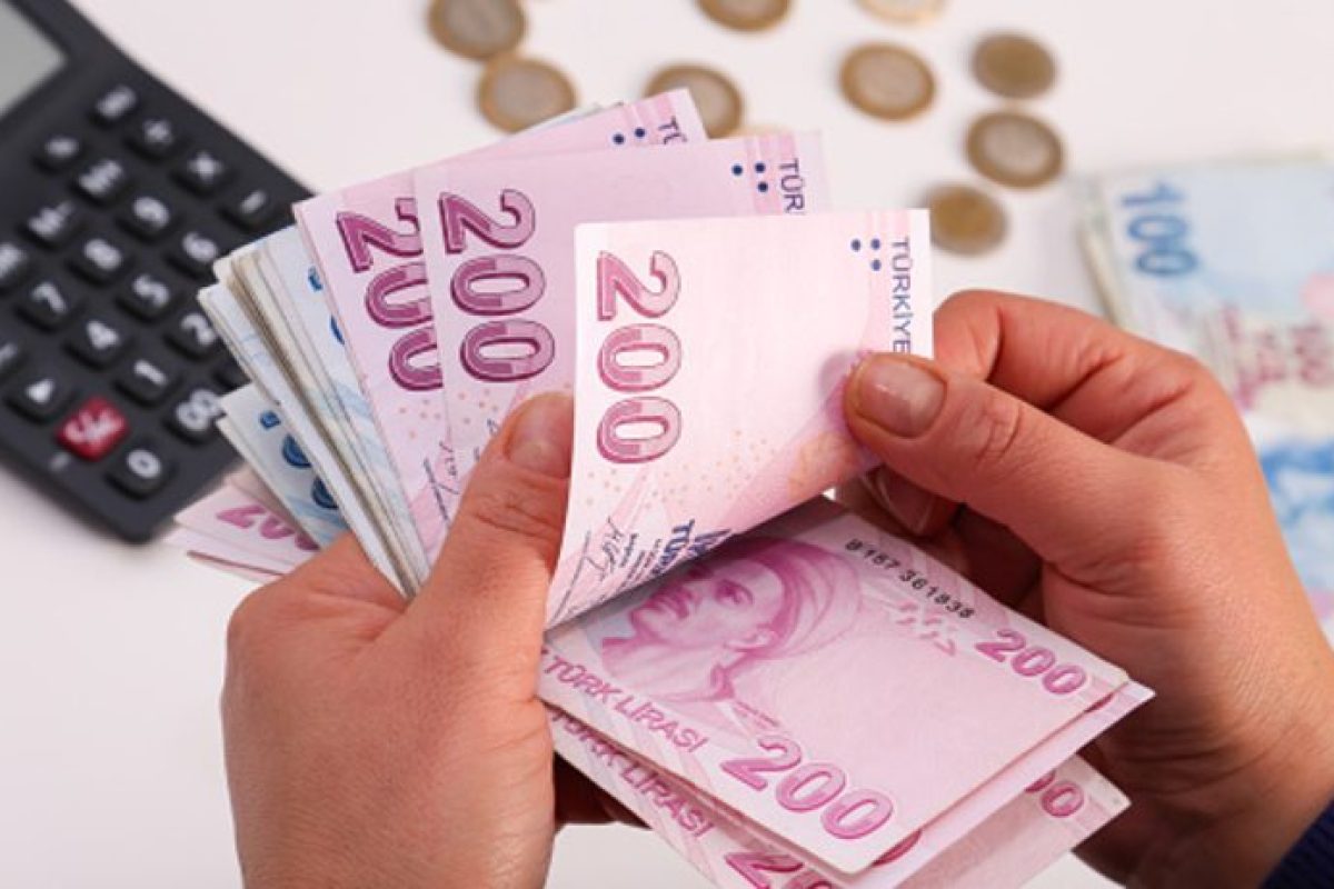 Unrecognizable person counting Turkish banknotes. Uses a calculator. Horizontal composition, studio shot, indoors shot